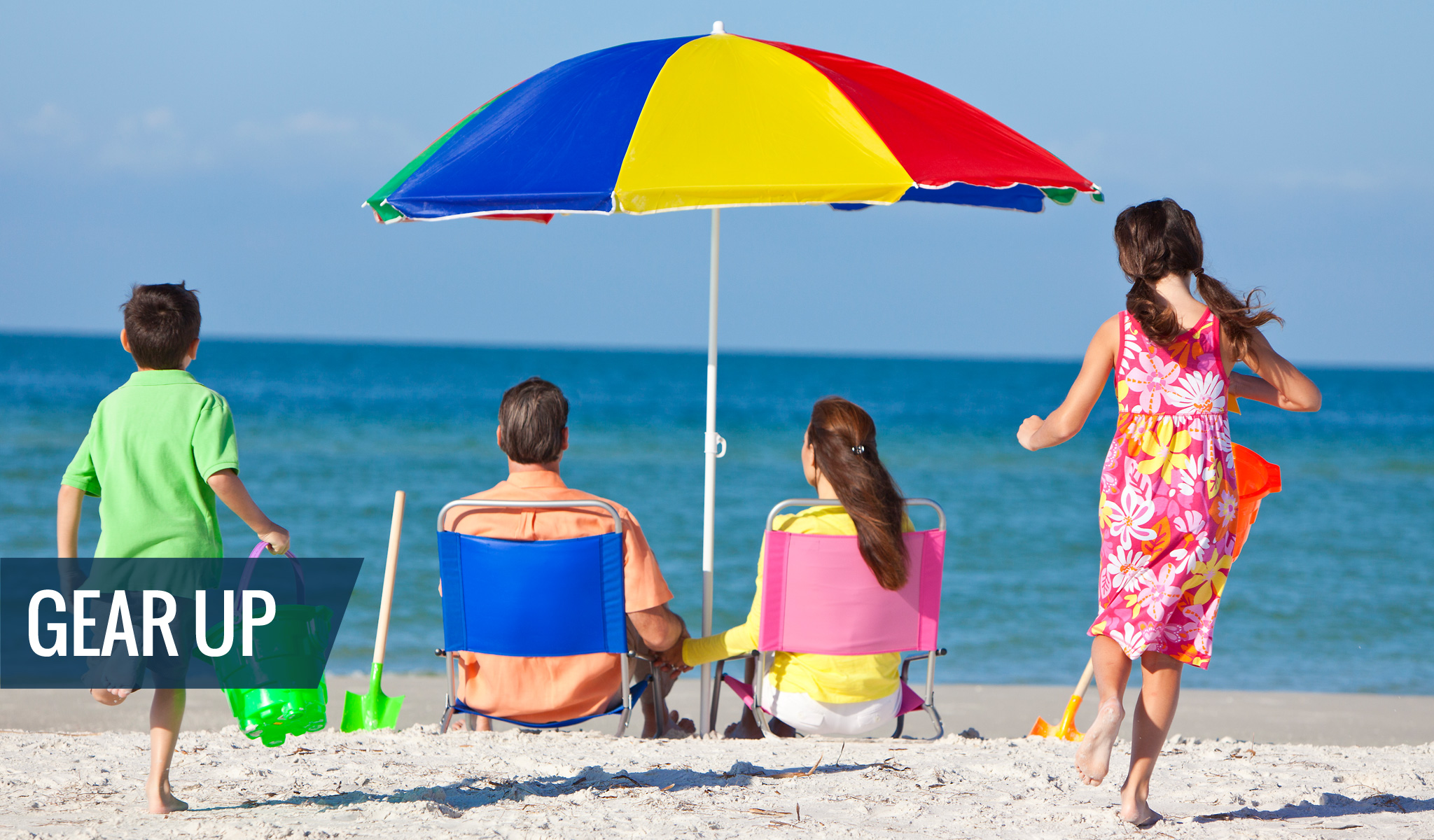A family with beach rental gear - umbrellas, chairs, beach toys